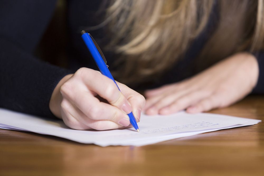 A closeup image of a woman signing a contract