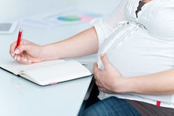 pregnant woman writing on a notepad