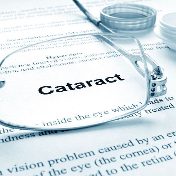 Eyeglasses magnifying the word 'cataract' on a paper