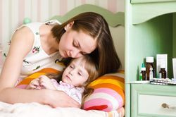 Mother tending to sick daughter in bed next to medication bottles